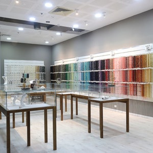 May include: A jewelry store interior with a wall of colorful beads and glass display cases. The sign above the display cases reads "Choose your COLOR Choose your ENERGY".