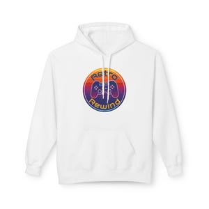 May include: White hoodie with a front pocket and drawstring. The hoodie features a circular graphic with a retro video game controller design. The graphic has the words "Retro Rewind" in a gradient of orange, purple, and blue.