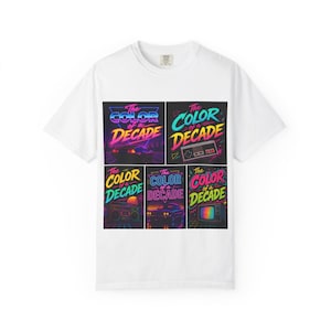 May include: White t-shirt featuring a colorful graphic design. The design includes the text "The Color of a Decade" in a retro font, along with images of a car, a video game controller, a boombox, and a television.