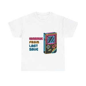 May include: White t-shirt featuring a neon-style graphic of a handheld gaming device. The design includes the text "CONTINUE FROM LAST SAVE" in pink and blue, evoking a retro video game aesthetic.