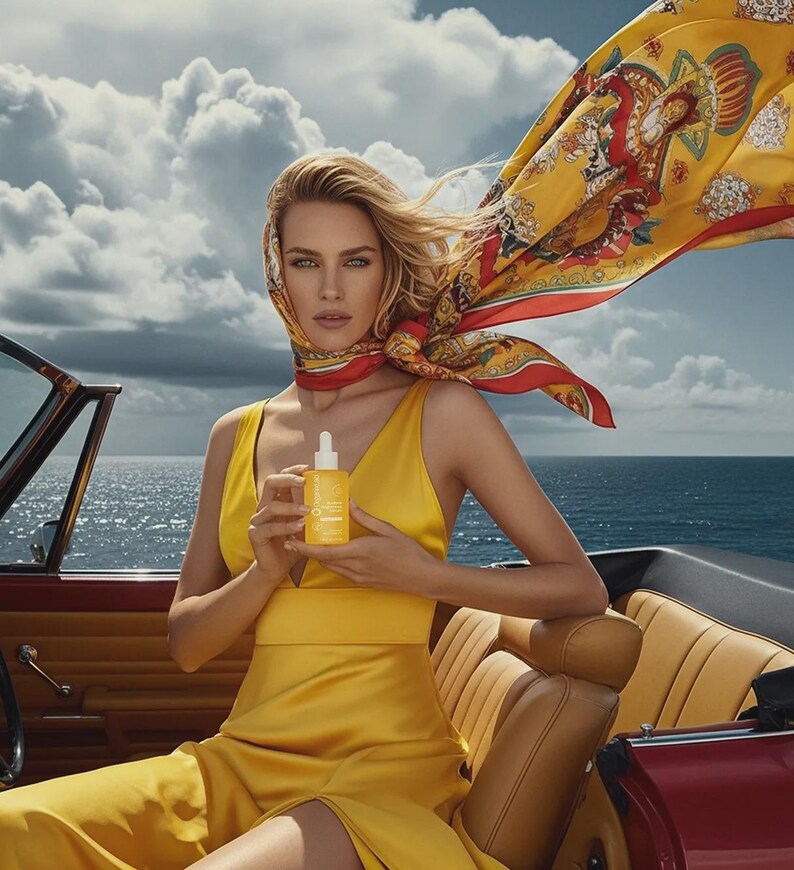 May include: A woman in a yellow dress and headscarf holds a yellow bottle with a dropper. The woman is seated in a red convertible with the ocean and sky in the background. The headscarf is yellow with a red border and a decorative pattern.