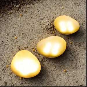 May include: Three glowing, golden-yellow, egg-shaped lights are arranged on a textured, grey surface. The lights have a soft, diffused glow. The surface has small pebbles and a rough texture. The lights appear to be illuminated.