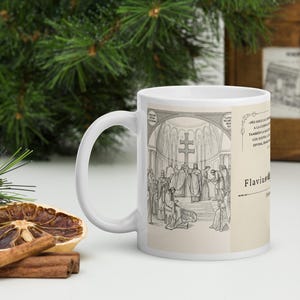May include: A white ceramic mug featuring a black and white historical illustration of a religious ceremony with a double-barred cross. The design includes Spanish text that reads No solo la compasión a la cuenta de los sueños, también la muerte, los sueños, a la vida, divida, hemos de ver and Flavius.