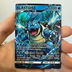 May include: A Blastoise Pokémon trading card with a blue, metallic finish. The card displays the name Blastoise, 330 HP, and two attacks: Hydro Eruption and Tidal Crash. The artwork features the blue turtle character firing water cannons.