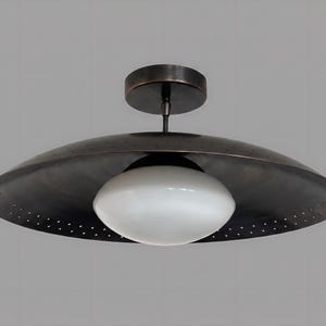 May include: A modern ceiling light fixture with a dark bronze finish. The fixture features a large, saucer-shaped shade with small perforations and a white, oval-shaped glass diffuser. The light is mounted on a circular base.