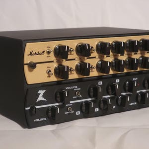 May include: A black and gold amplifier with multiple knobs and the text "Marshall" and "JMP" on the top section. The bottom section is black with the text "Z" and "Wreck". The amplifier has a variety of controls for volume, speed, and tone.