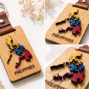 Puede incluir: Llavero de madera con un mapa detallado de Filipinas en amarillo, azul y rojo. Tiene una correa de cuero marrón y un anillo plateado. La palabra "PHILIPPINES" está grabada en la superficie de madera. Un accesorio decorativo.