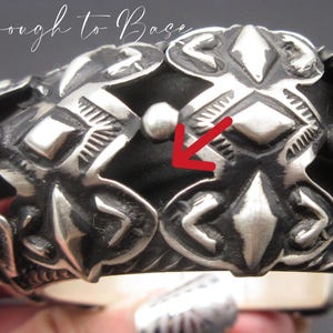 May include: Silver bracelet with an intricate geometric design. The bracelet is made of multiple pieces that are joined together to create a unique and eye-catching pattern.