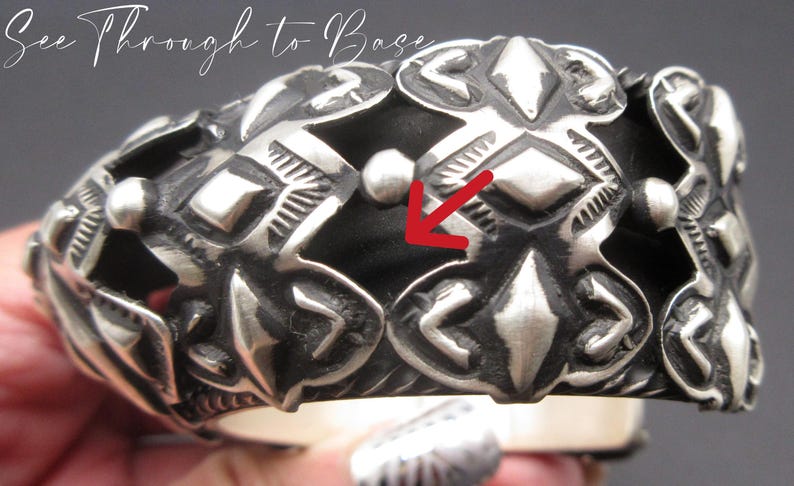 May include: Silver bracelet with an intricate geometric design. The bracelet is made of multiple pieces that are joined together to create a unique and eye-catching pattern.