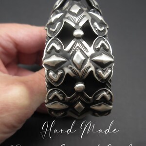 May include: A silver bracelet with a hand-made repousse stamped concho design. The bracelet is made of silver and has a geometric pattern.