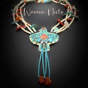 May include: A turquoise, coral, and white beaded necklace with a Thunderbird pendant. The necklace features the text "Warren Nieto" and "Ancestral Puebloan Thunderbird Heishi Necklace". The pendant is a mosaic of turquoise and coral.