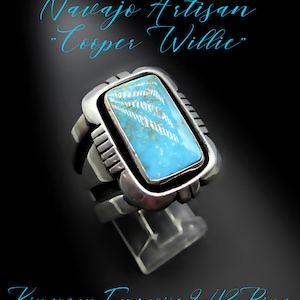 May include: A silver ring with a rectangular turquoise stone. The turquoise is light blue with white and brown markings. The ring has a thick band and a decorative setting. Text on the image reads "Navajo Artisan 'Cooper Willie'" and "Kingman Turquoise 9-1/2 Ring."