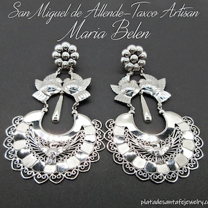 May include: Silver earrings with a crescent moon design, two doves, and a teardrop pendant. The earrings are handmade in Taxco, Mexico by Maria Belen.