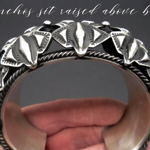 May include: Silver bracelet with a decorative design of raised conchos. The conchos are shaped like leaves and have a textured surface. "Conchos sit raised above base" is written on the top of the image.