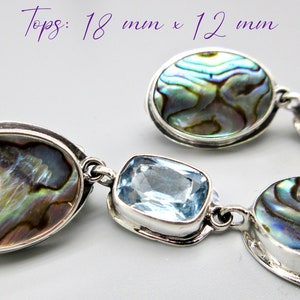 May include: A pair of silver earrings with oval-shaped abalone shell and blue topaz stones. Tops: 18 mm x 12 mm.