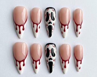 May include: A set of ten almond-shaped press-on nails featuring a nude base with white tips and red blood-drip accents. Two of the nails feature a black and white ghost-face mask design, mimicking a classic horror movie character aesthetic.