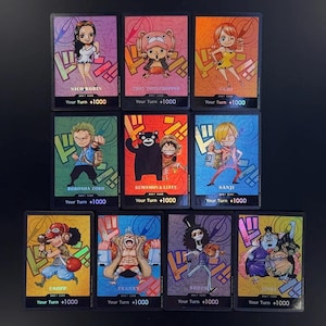 May include: A collection of ten One Piece Don! trading cards featuring colorful anime character illustrations including Nico Robin, Tony Tony Chopper, Nami, Roronoa Zoro, Kumamon and Luffy, Sanji, Usopp, Franky, Brook, and Jinbe with text Your Turn +1000.
