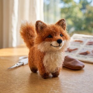 May include: A handcrafted, orange and white fox figurine with a fluffy tail and a smiling expression. The fox is standing on a wooden surface. The fox is approximately 13 cm tall.