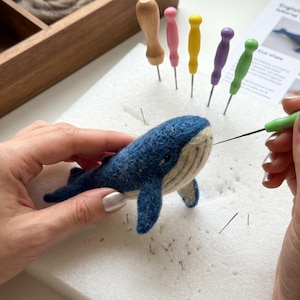Può includere: Un progetto artigianale di balena blu realizzato con lana infeltrita ad ago nei toni del blu scuro e crema. La balena viene lavorata con un ago da infeltrimento verde. Sono presenti aghi colorati, un cuscinetto in schiuma e una scatola.