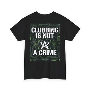 Puede incluir: Camiseta negra con la frase "CLUBBING IS NOT A CRIME" en blanco. El diseño incluye un gráfico verde estilo circuito impreso y un símbolo de estrella estilizado. Cuello redondo, manga corta.
