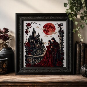May include: A framed cross-stitch embroidery depicting a couple in dark red and black attire standing before a gothic castle under a large red moon. The scene is framed by red roses and stone pillars, all rendered in a detailed pixelated stitch pattern.