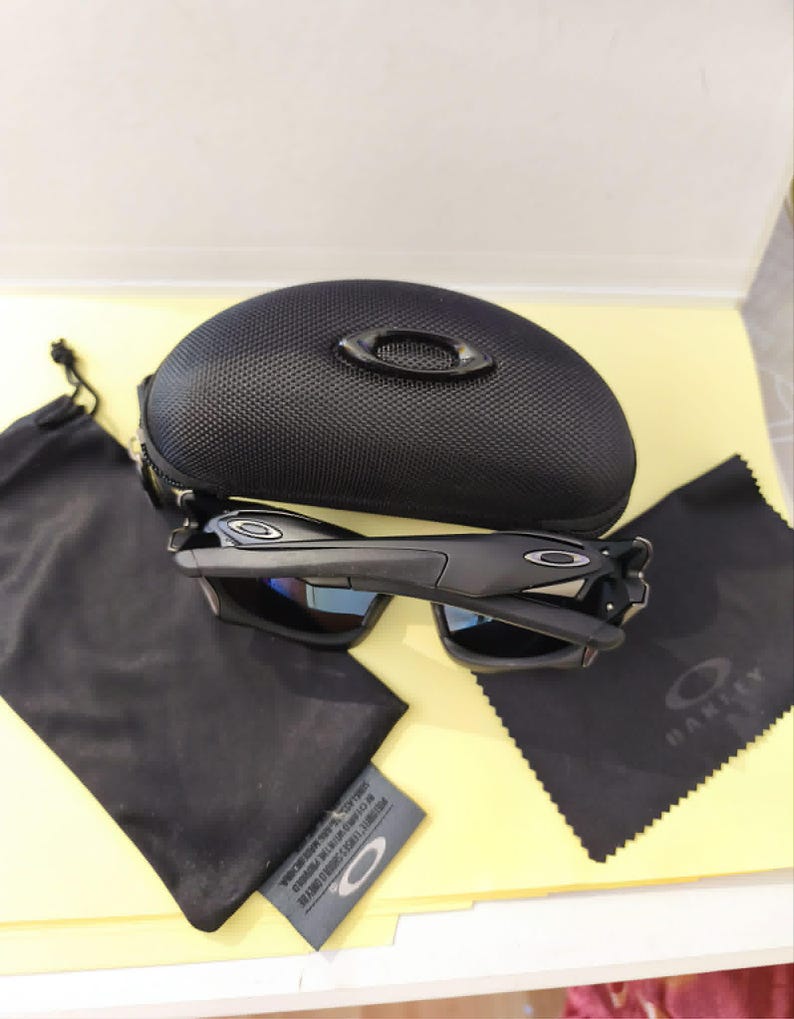 Puede incluir: Gafas de sol negras con estuche a juego, pa&ntilde;o de microfibra y bolsa con cord&oacute;n. Las gafas tienen un dise&ntilde;o elegante con lentes oscuras y montura negra. El estuche es texturizado y tiene un peque&ntilde;o logotipo.