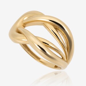 Può includere: Un anello color oro con un design unico e intrecciato. L'anello presenta una serie di fasce lisce e curve che si intersecano per creare una forma geometrica aperta. La superficie lucida riflette la luce, evidenziando la forma intricata dell'anello.