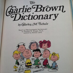May include: The Charlie Brown Dictionary book cover features a group of Peanuts characters including Charlie Brown, Snoopy, Lucy, Linus, and Sally. The book is based on The Rainbow Dictionary by Wendell W. Wright, Ph.D., assisted by Helene Laird.