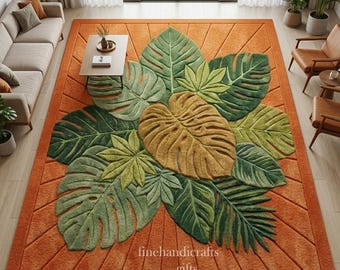 Puede incluir: Una alfombra rectangular naranja con un diseño de hojas grande y detallado en tonos verdes y beige. La alfombra presenta una superficie texturizada y el texto "finehandicrafts gifts" en la esquina inferior derecha.