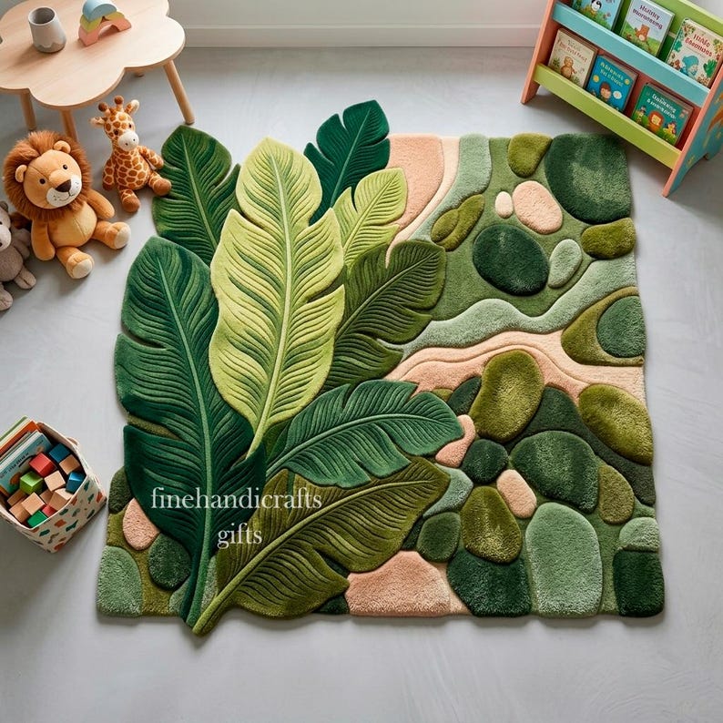 Puede incluir: Una alfombra de pelo insertado con un gran dise&ntilde;o bot&aacute;nico que presenta hojas de palmera verdes superpuestas en un lado y un patr&oacute;n texturizado de formas redondeadas similares a guijarros en tonos verdes y melocot&oacute;n suave. El texto finehandicrafts gifts es visible.