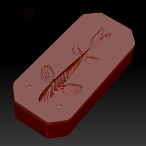 May include: A rectangular, reddish-brown silicone mold featuring a recessed, detailed impression of a fish with textured fins and a long body. The mold has two small circular indentations near the head of the fish design on a flat surface.