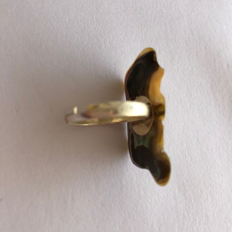 May include: A silver ring with a gold-toned, irregularly shaped stone. The stone has a green and brown pattern.