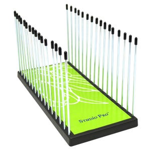 May include: A black Studio Pro tool with a bright green base featuring a white leaf design. The tool has numerous silver rods topped with black caps, arranged in a V-shape.