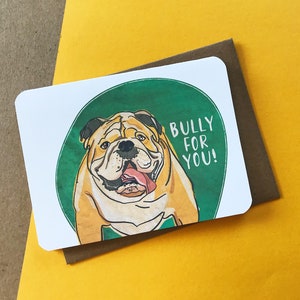 May include: A greeting card with a green circle and a cartoon bulldog with a tongue sticking out. The text inside the circle says "Bully for you!"