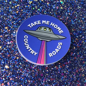 May include: A blue and white round sticker with a cartoon UFO and the text "Take Me Home Country Roads".
