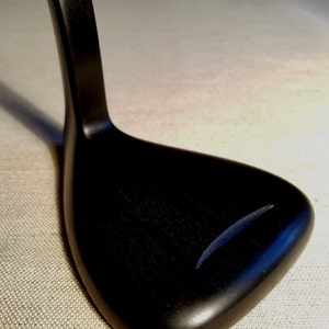 May include: A black wooden guitar stand with a curved neck and a flat base. The stand is made of a dark wood with a smooth finish.