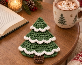 May include: A green crochet coaster shaped like a Christmas tree with three tiers of white scalloped trim along the edges and a small brown rectangular base at the bottom, crafted with a textured yarn stitch pattern for a decorative table accent.