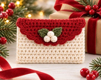 May include: A rectangular crochet pouch featuring a cream-colored body and a scalloped red flap. The center of the flap is decorated with two green crocheted leaves and three small white crocheted spheres arranged to resemble a holly berry cluster.