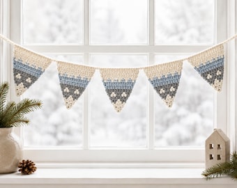 May include: A crochet bunting banner featuring five triangular pennants suspended on a string. Each pennant displays a horizontal color gradient pattern transitioning from cream at the top to light blue, medium blue, dark gray, and white at the tip.