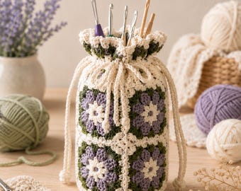May include: A cylindrical crochet drawstring bag featuring a granny square pattern with cream, lavender, and dark green yarn. The bag has a ruffled top edge and contains several metal and wooden crochet hooks stored upright inside the pouch.