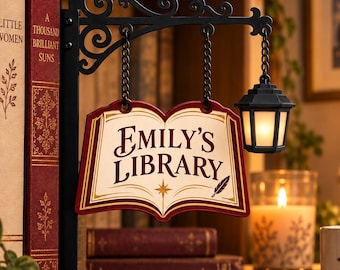May include: A black metal wall-mounted sign bracket with a hanging open book-shaped plaque that reads Emily's Library in dark red lettering. The sign features a small attached lantern and decorative scrollwork, suspended by chains from the metal arm.