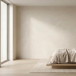 May include: A minimalist bedroom with a light wood bed frame and beige bedding. A black nightstand holds a vase and decorative branches. Large windows provide natural light, and the walls are painted in a neutral tone. The room has a rug and light wood flooring.