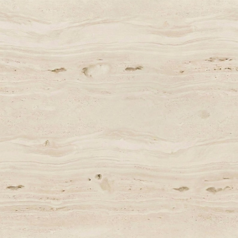 May include: A close-up of a beige stone surface with a natural, layered pattern. The stone has subtle variations in color and texture, with small, dark spots scattered throughout. The overall appearance is smooth and organic.