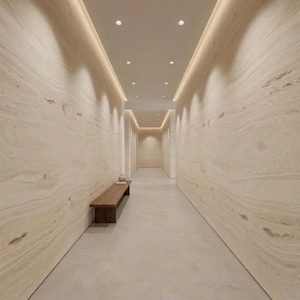 May include: A long hallway with beige walls and a light-colored floor. Recessed lighting illuminates the space. A wooden bench and decorative items sit near the entrance. The walls have a natural stone pattern.