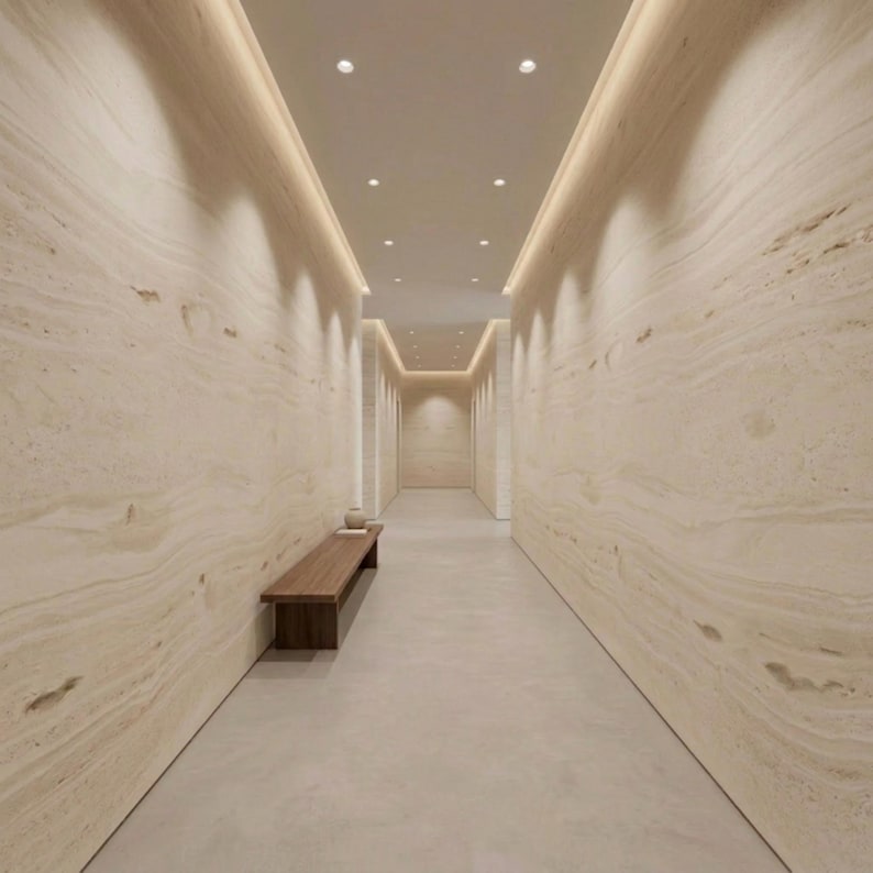 May include: A long hallway with beige walls and a light-colored floor. Recessed lighting illuminates the space. A wooden bench and decorative items sit near the entrance. The walls have a natural stone pattern.