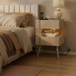 May include: A light wood nightstand featuring a rectangular frame with four tapered legs, a top surface for charging devices, and an open middle compartment with integrated warm lighting containing a pair of headphones and stacked books.