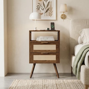 May include: A dark wood nightstand featuring an open top shelf and two drawers with light-colored woven cane panels. The nightstand has four tapered legs and horizontal gold-toned metal drawer pulls. Two books are stacked on the open shelf.