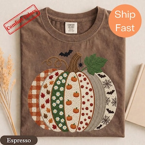 Peut inclure: Un t-shirt couleur espresso avec un grand motif de citrouille brodé. La citrouille est divisée en segments verticaux avec des motifs incluant du vichy orange, des feuilles d'automne, des marguerites blanches, des petites citrouilles, des pois rouges, un motif à chevrons et des toiles d'araignée avec des chauves-souris.