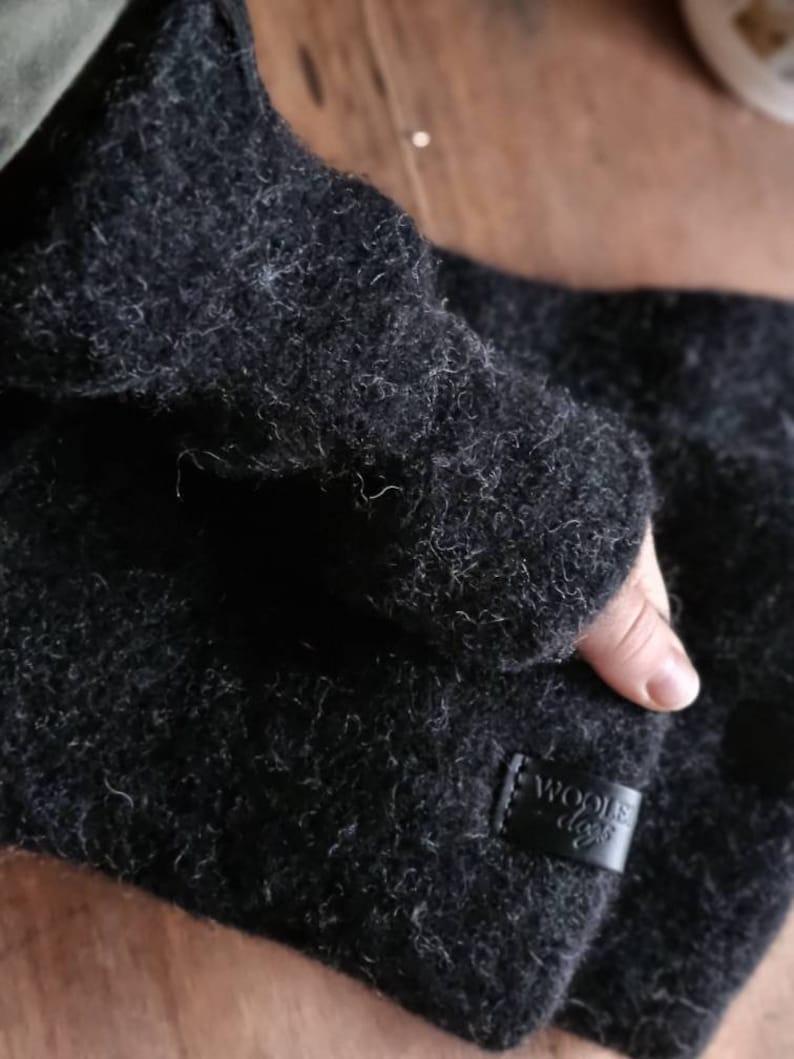 May include: Black wool fingerless gloves with a leather patch that says "Woolie Days".