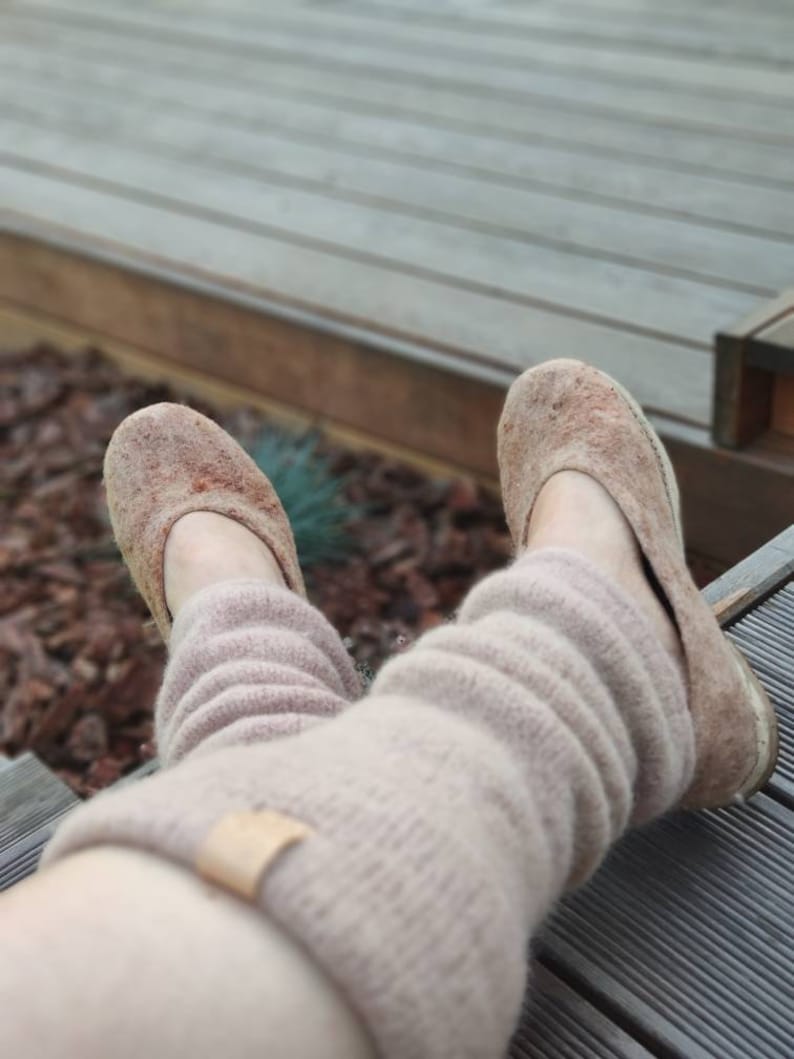 May include: A pair of brown felt slippers with a light brown knitted leg warmer. The slippers are worn and have a worn look.